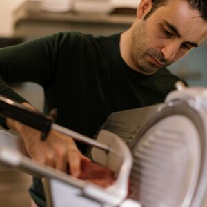 person using a meat slicer to cut meat